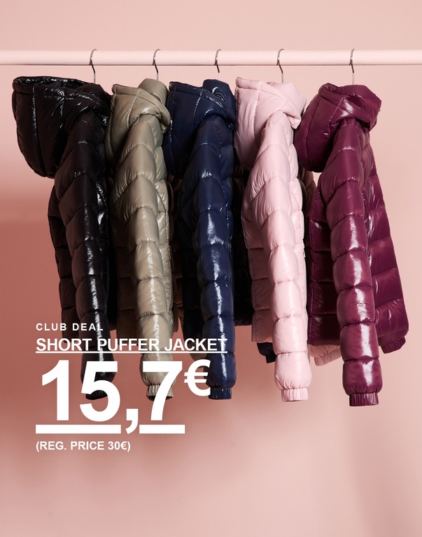 Kurze Pufferjacken für Kinder in verschiedenen Farben hängen an einer Kleiderstange. CLUB DEAL – SHORT PUFFER JACKET 15,70 € (REG. PRICE 30 €).