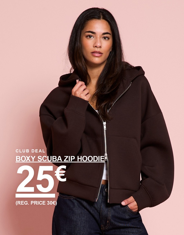 Meid in een bruine boxy scuba zip hoodie. Campagnetekst: ‘BOXY SCUBA ZIP HOODIE, 25€ (VAN 30€)’.