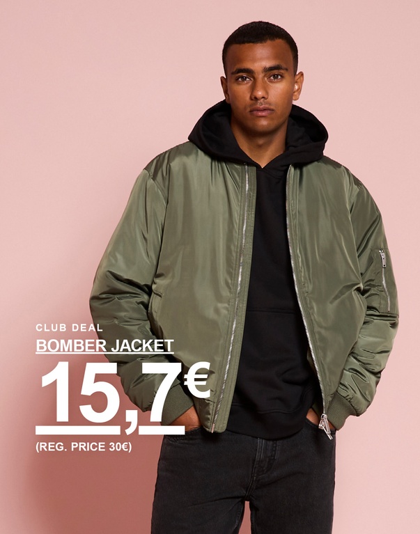 Ein Mann in grüner Bomberjacke über einem schwarzen Hoodie. Kampagnentext: „CLUB DEAL BOMBER JACKET 15,7€ (REG. PRICE 30€)“.