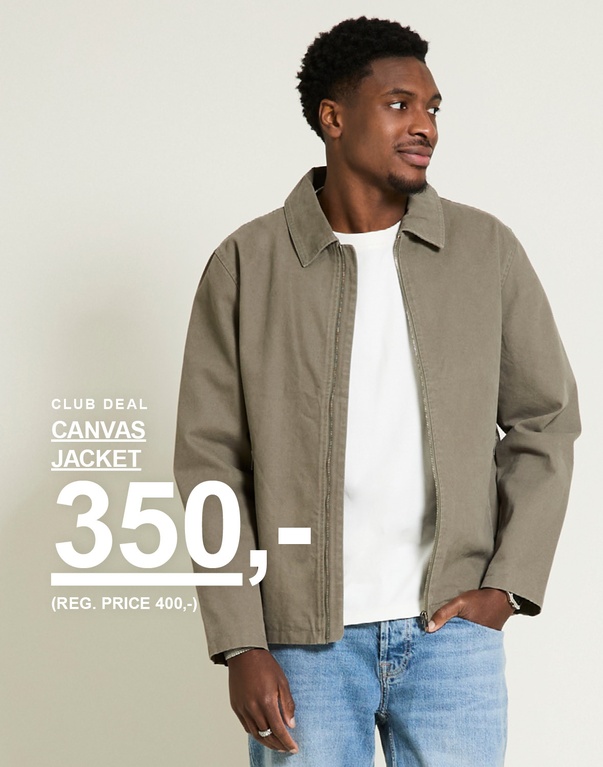 Mann i olivengrønn canvas jacket med hvit t-skjorte og lyse jeans mot lys bakgrunn. Club deal canvas jacket 350,- (reg. price 400,-)