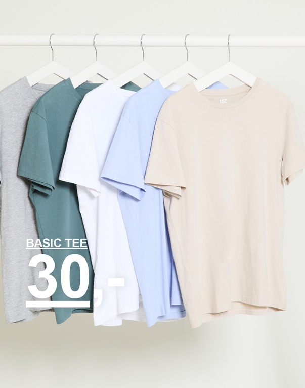 Flere ensfargede t-skjorter i grått, grønt, hvitt, lyseblått og beige på kleshengere mot lys bakgrunn. Basic tee 30,-