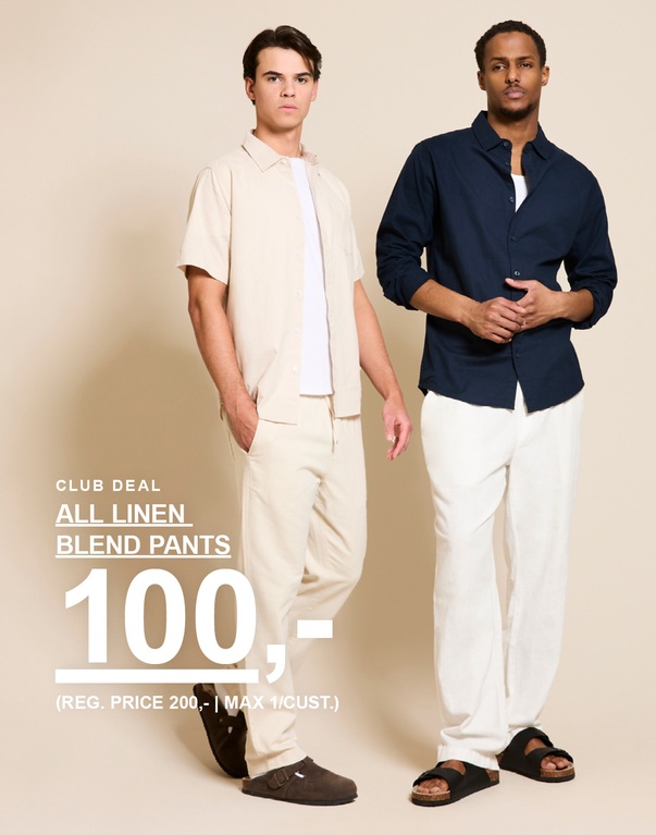 To menn i linblandede antrekk – en i beige kortermet skjorte og bukse, en i mørkeblå skjorte og hvite bukser mot lys bakgrunn. Club deal. All linen blend pants 100,- (Reg. price 200,-) Max 1/cust.
