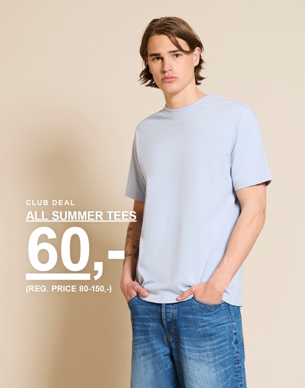 Mann i lyseblå t-skjorte og jeans foran beige bakgrunn. CLUB DEAL. ALL SUMMER TEES 60,- (REG. PRICE 80-150,-)
