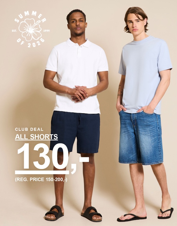 To menn i shorts og t-skjorter – hvit piqué med mørkeblå shorts og lyseblå t-skjorte med jeansshorts foran beige bakgrunn. CLUB DEAL. ALL SHORTS 130,- (REG. PRICE 150-200,-)