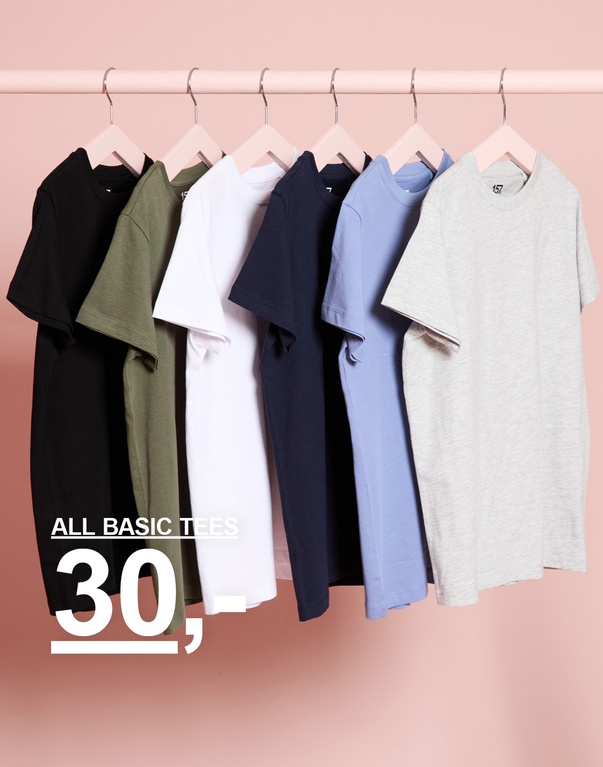 Basic T-skjorter for barn i flere farger henger på en klesstang. ALL BASIC TEES 30,-.