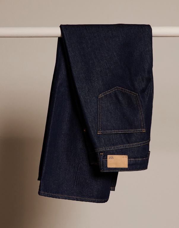 En stapel vikta jeans i olika nyanser av blått och grått. Text: "DENIM" med information om ett brett jeansutbud för alla åldrar och kroppstyper, med fokus på passform, kvalitet och hållbarhet.