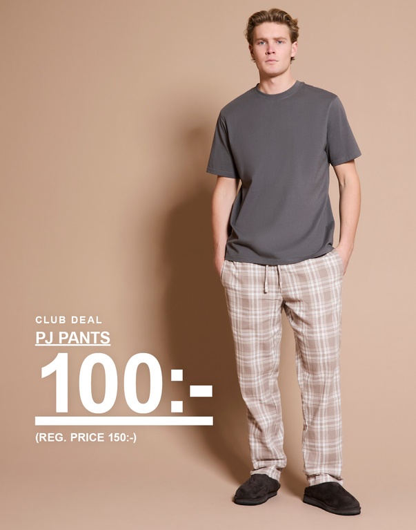 Man i grå t-shirt och rutiga pyjamasbyxor med mörka tofflor mot ljus bakgrund. Kampanjtext: ”CLUB DEAL PJ PANTS 100:- (REG. PRICE 150:-)”.