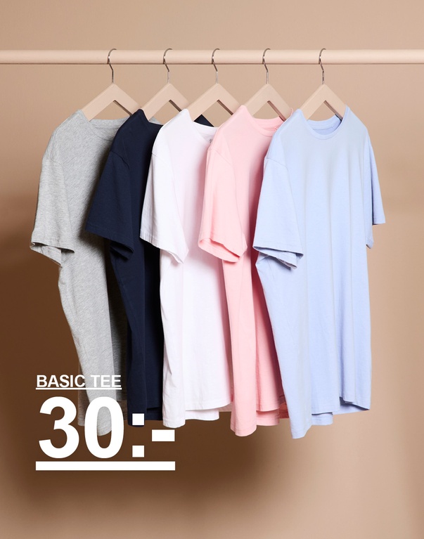 Flera enfärgade t-shirts i olika färger på galgar mot ljus bakgrund. Kampanjtext: ”BASIC TEE 30:-”.