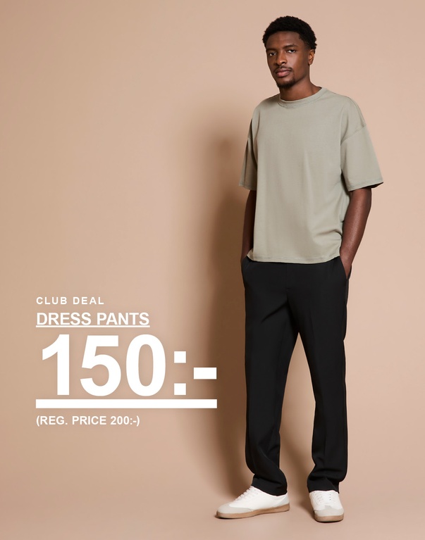 Man i ljusgrön t-shirt och svarta dress pants med vita sneakers mot beige bakgrund. Kampanjtext: “CLUB DEAL DRESS PANTS 150:- (REG. PRICE 200:-)”.