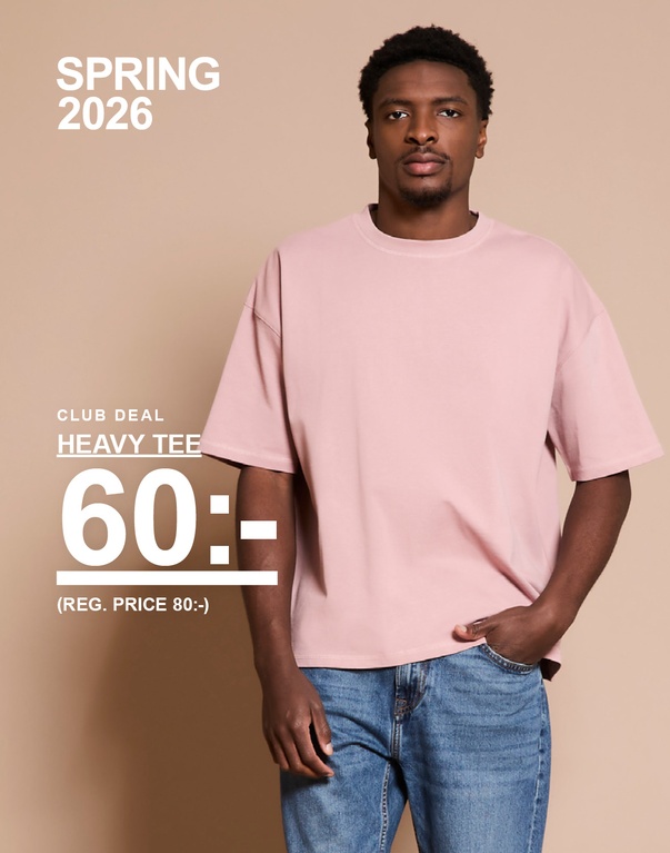 Man i rosa heavy tee och blå jeans mot beige bakgrund. Kampanjtext: “CLUB DEAL HEAVY TEE 60:- (REG. PRICE 80:-)”.