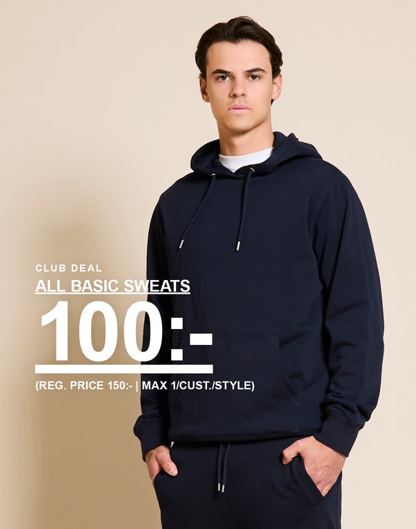Man i mörkblå hoodie och sweatpants framför beige bakgrund. CLUB DEAL. ALL BASIC SWEATS 100:- (REG. PRICE 150:- | MAX 1/CUST./STYLE)