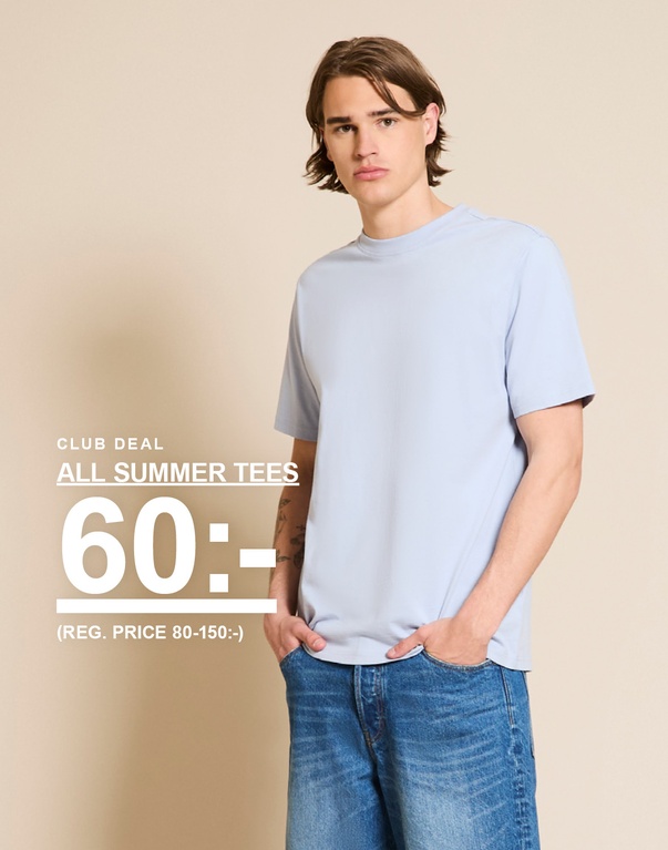 Man i ljusblå t-shirt och jeans framför beige bakgrund. CLUB DEAL. ALL SUMMER TEES 60:- (REG. PRICE 80-150:-)
