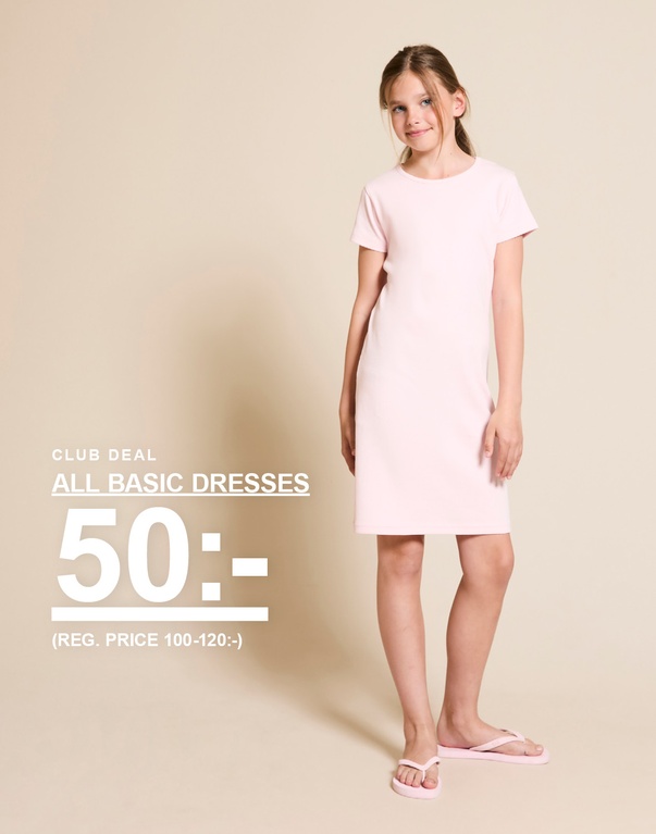 Flicka står framför en ljus bakgrund iklädd en ljusrosa basklänning och matchande flip-flops. CLUB DEAL ALL BASIC DRESSES 50:- (REG. PRICE 100-120:-)