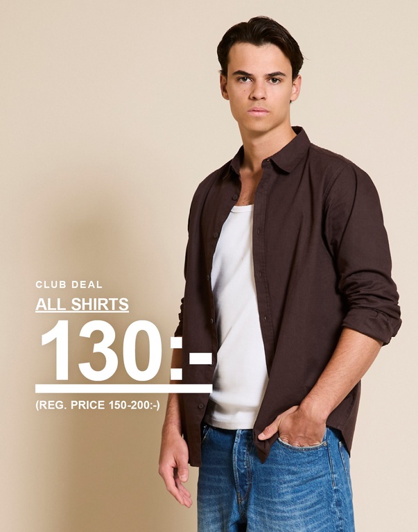 Man i mörkbrun skjorta över vit topp och blå denimshorts. CLUB DEAL. ALL SHIRTS 130:- (REG. PRICE 150-200:-)