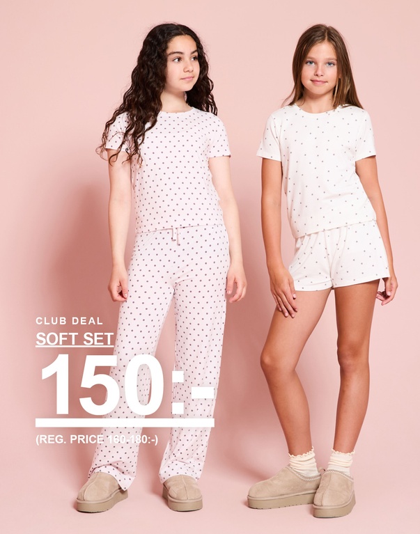 Två barn bär mjuka matchande set med t-shirt och byxor eller shorts. Club Deal: soft set 150 kr. Ord. pris: 160–180 kr.