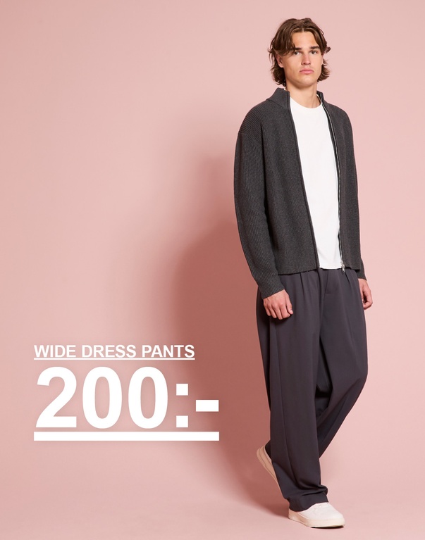 Kille i mörkgrå stickad tröja och vida byxor. Kampanjtext: "WIDE DRESS PANTS 200:-"
