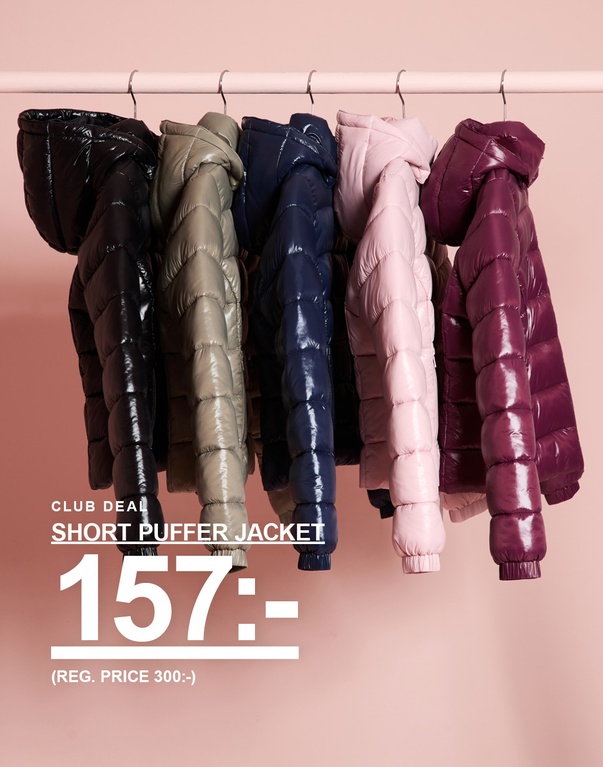 Korta pufferjackor för barn i flera färger hänger på en klädstång. CLUB DEAL – SHORT PUFFER JACKET 157:- (REG. PRICE 300:-).