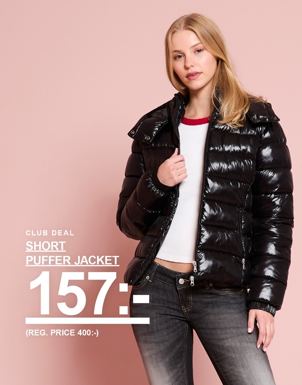 Tjej i svart glansig kort pufferjacka. Kampanjtext: ”CLUB DEAL – SHORT PUFFER JACKET 157:- (REG. PRICE 400:-)”.