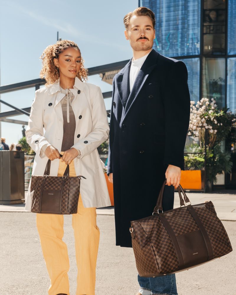 Man med en mörkbrun weekendbag ute i stan