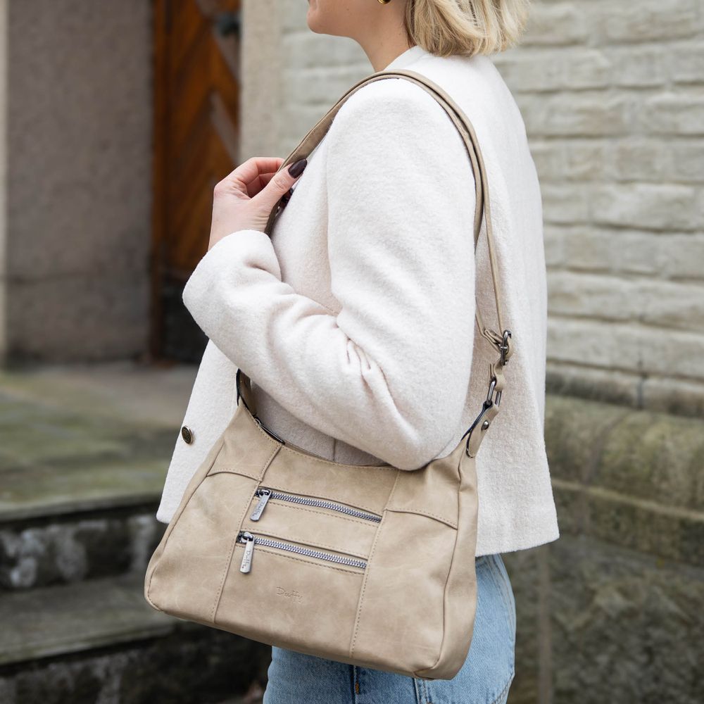 Ljusbeige axelväska Duffy med dragkedjefickor som bärs över axeln.