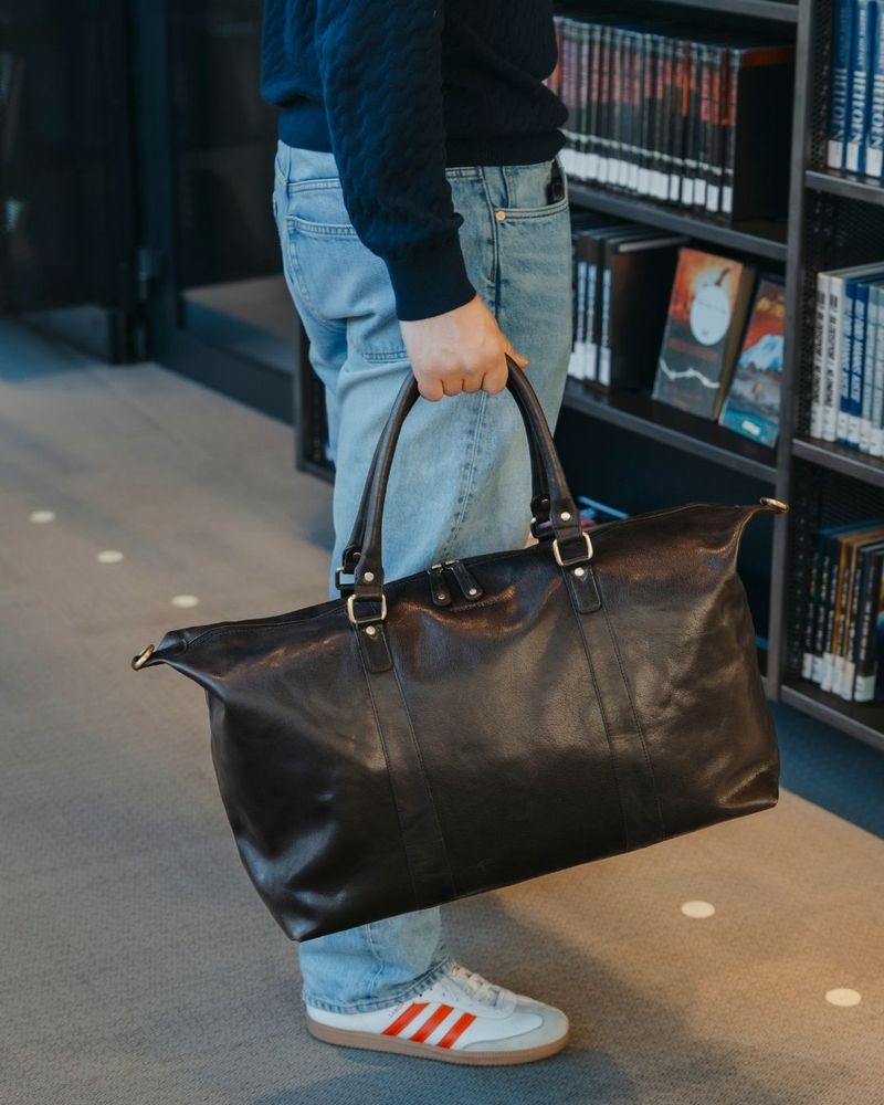 Man med en mörkbrun weekendbag i läder.