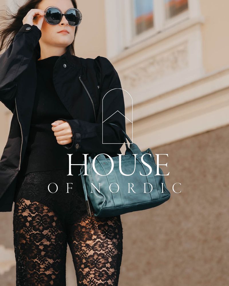 Svart handväska som bärs av person i svart outfit framför stadsmiljö. House of Nordic logo