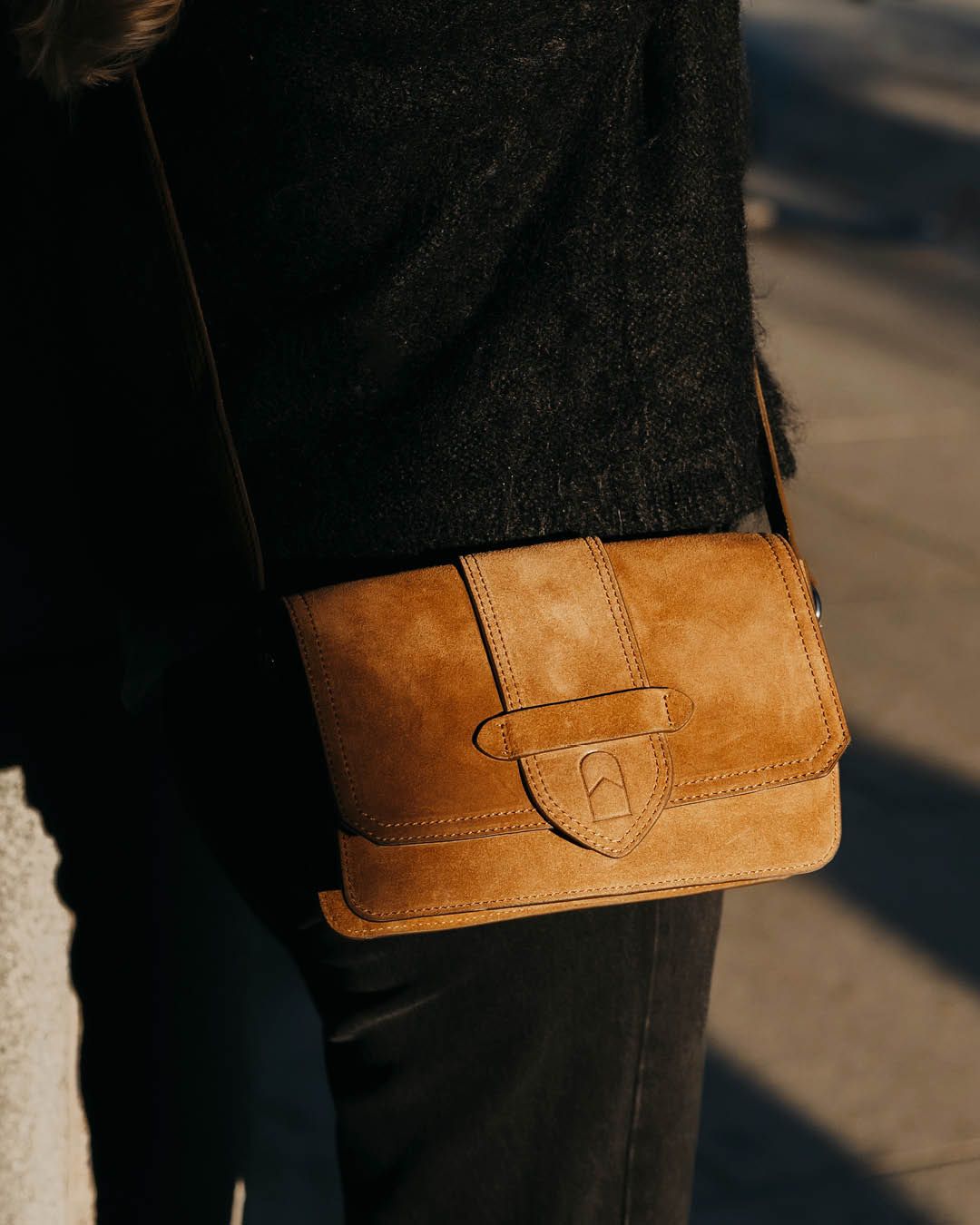 Brun crossbodyväska i mocka från House of Nordic, buren över axeln, med klaff och dekorativ söm.