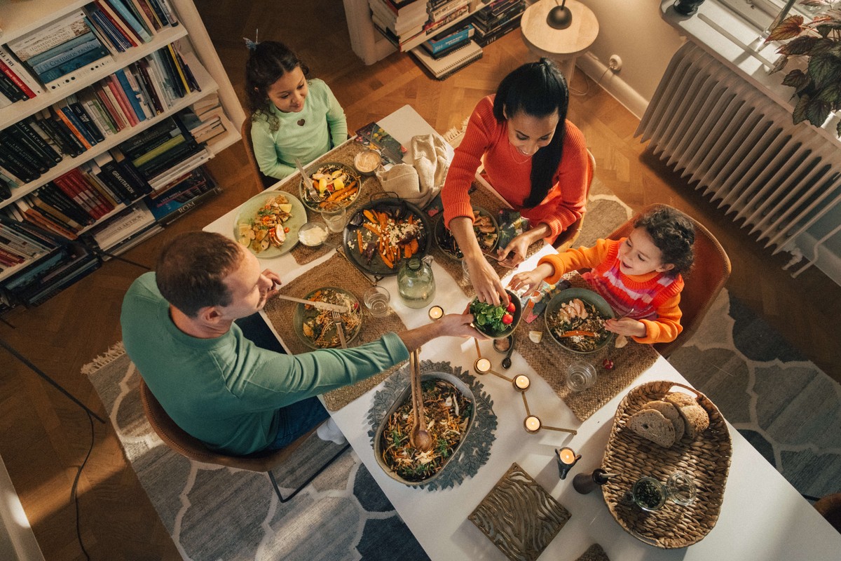 Familj med två barn som äter middag med tända ljus