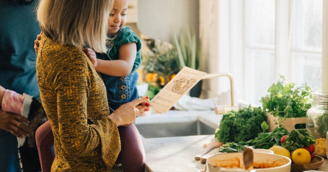 Mamma med barn läser recept vid köksbänk