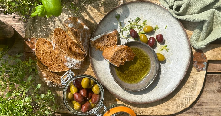 Baguette och oliver som doppas i olivolja