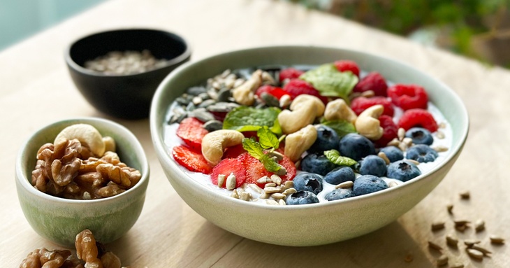 Skål med yoghurt, nötter, blåbär och frukter
