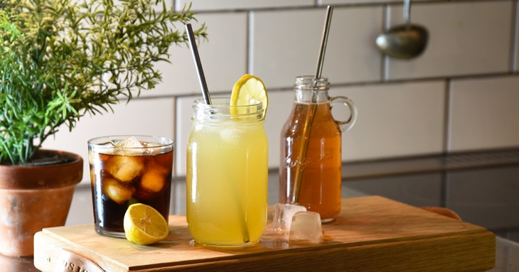 Glasbägare och glas på en skärbräda med sötad dryck och citron