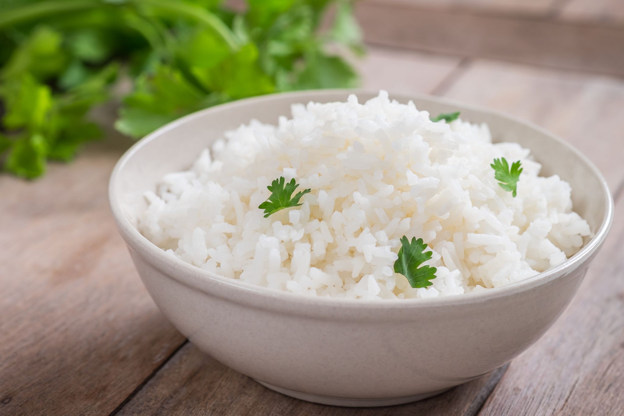 En skål med vitt ris som toppas med persilja.