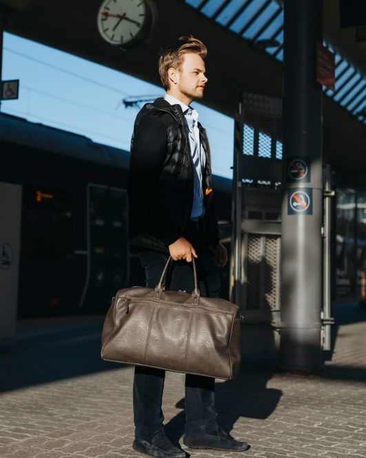 Mann med en weekend bag på en togstasjon
