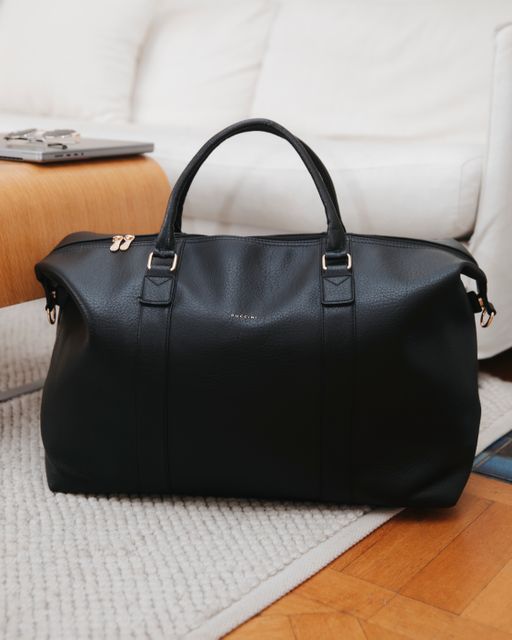 Sort weekendbag står på gulvet i en stue
