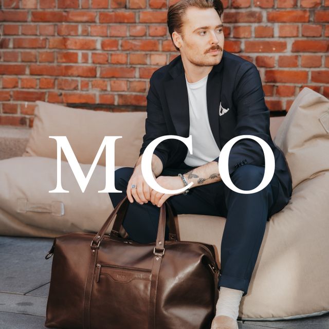 MCO brun weekendbag skinn står på gulv fremfor mann