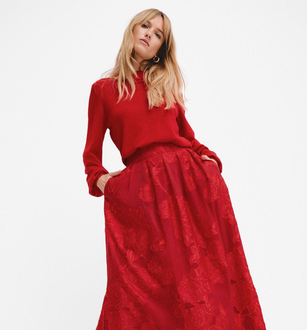 Dame i festlig rød nederdel og en rød finstrikket trøje.