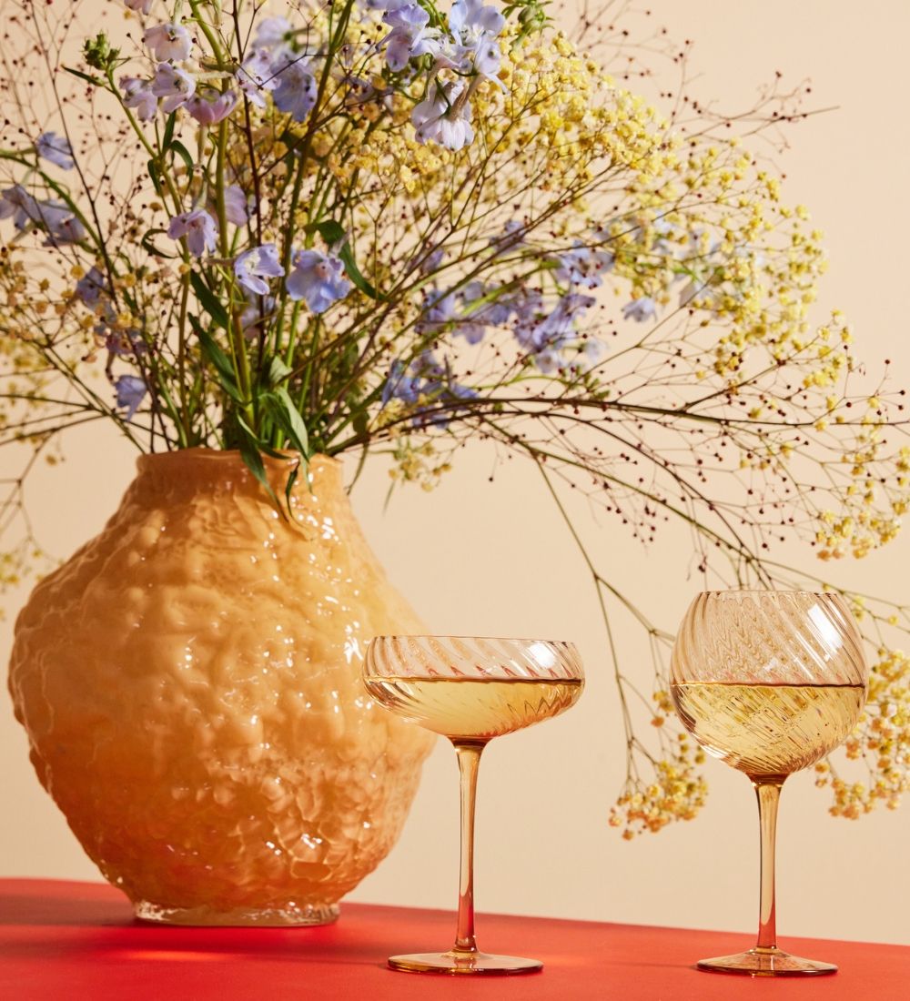 Ett dukat bort med vinglas och en gul vas med blommor