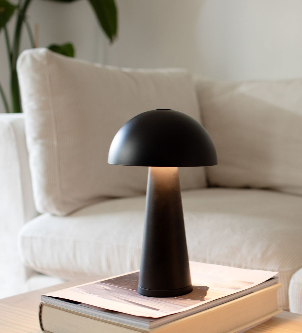 En svart svamplampa på ståendes på ett soffbord.