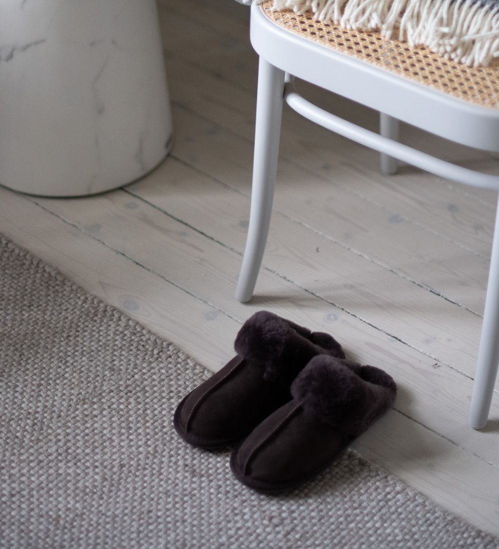 Två bruna mockatofflor på ett vitt trägolv