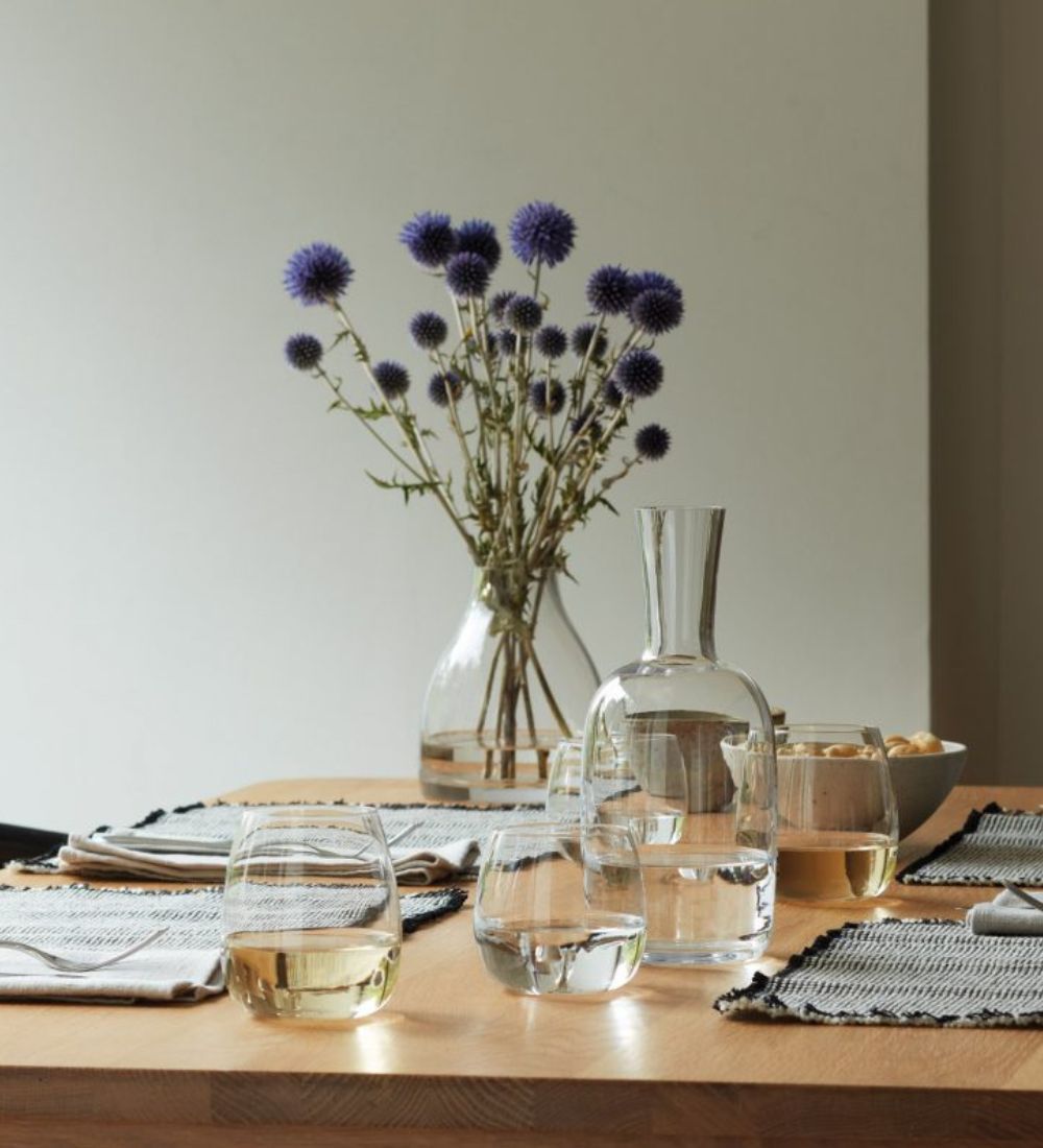 Ett vackert dukat bord med fint proslin och en vas med lila blommor