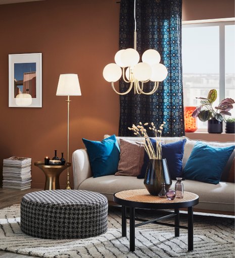 Ett stilrent vardagsrum med en guldiga taklampa från Markslöjd