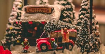 Dockor i ett vinterlandskap som lastar på en julgran på en bil