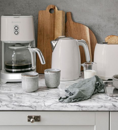 Vita köksmaskiner på en bänkskiva gjord av marmor