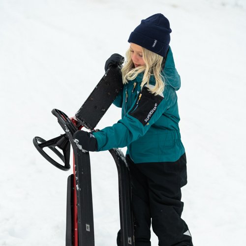 Gneis Supershape vinteroveral i petrol, vattentät, varm och smidig overall. Barn leker i snön med bob.