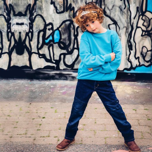 Gneis Ossoami Amigo jeans. Slitstarka, sköna jeans som tål tuffa tag. Barn som står framför graffitiplank.