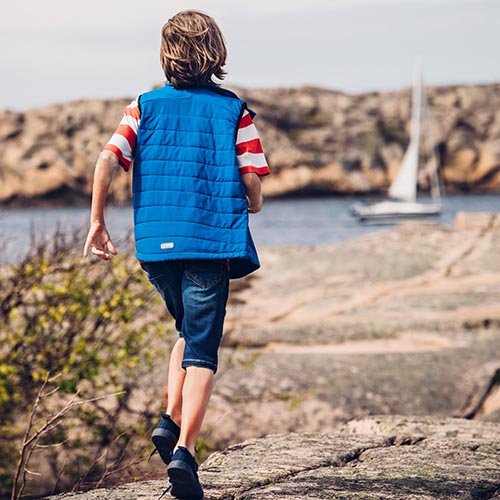 Barn går på klipporna i Ossoami Pard shorts från Gneis