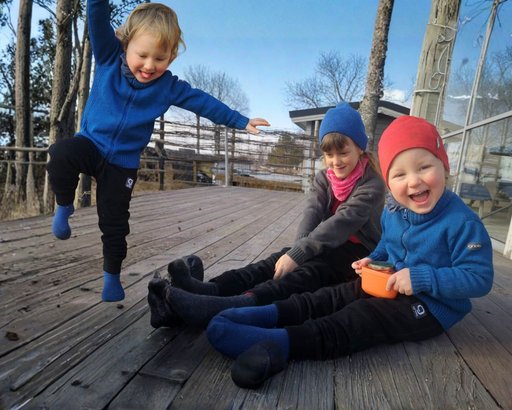 Tre barn som myser i solen med Gneis sköna mellanlager av merinoull på sig