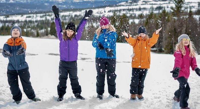 Glada barn i Gneis-kläder som kastar snö