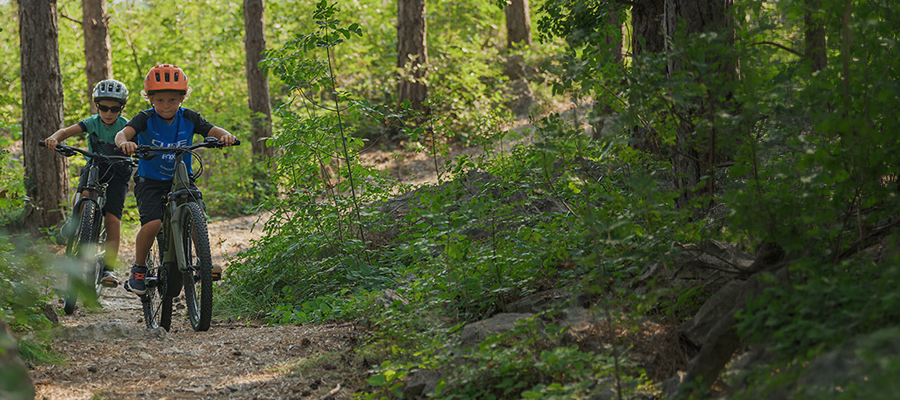 Kaksi lasta pyöräilee maastopyörällä maastossa.
